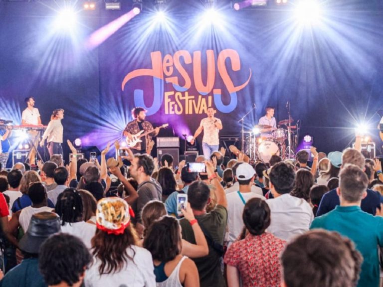 Des gens assistent à un concert de louange au Jesus Festival 2022, la scène est éclairée par des projecteurs