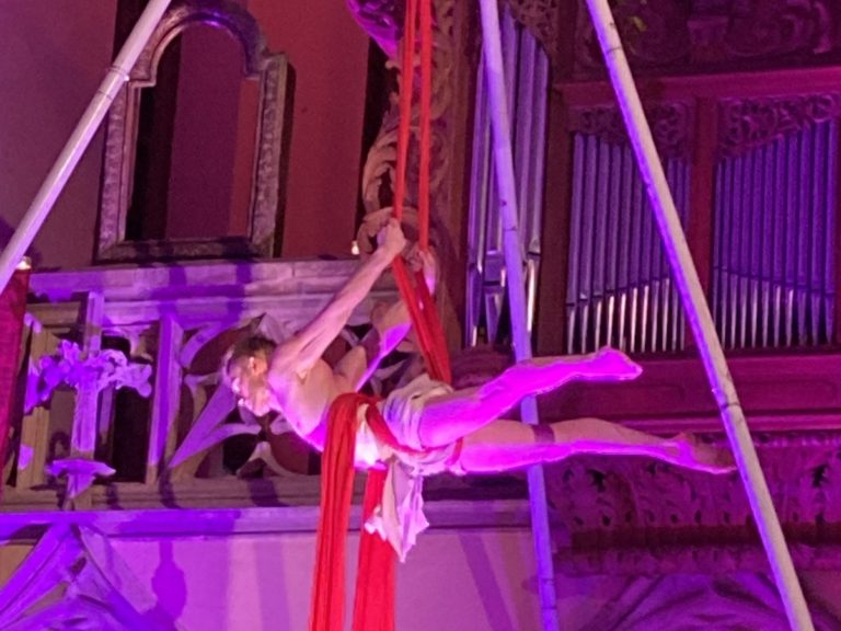 Un homme attaché à tissu effectue un spectacle de danse aérien devant un orgue d'une Eglise protestante