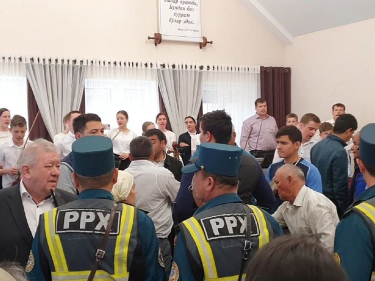 Des policiers en uniforme, képi sur la tête, interpellent des croyants dans une Eglise baptiste d'Ouzbékistan le dimanche de Pâques