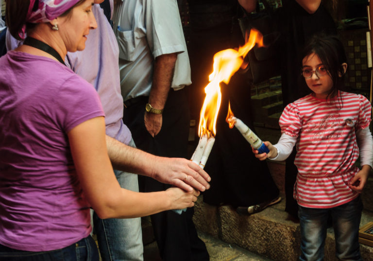 Une dame transmet la flamme de son flambeau à une petite fille