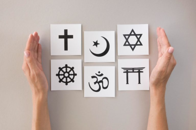 Des cartes représentant les symboles de 6 religions sont placées sur une table.