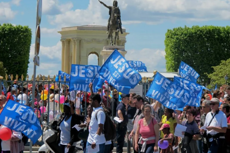 Une multitude de marcheurs, en ville, portent des drapeaux inscrits "Jésus est vivant"