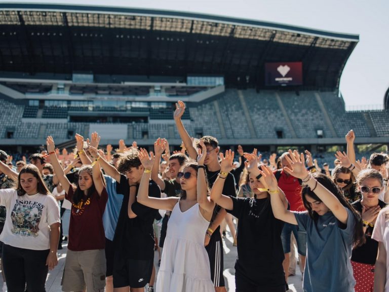 Des jeunes lèvent les mains vers le ciel dans un stade de football