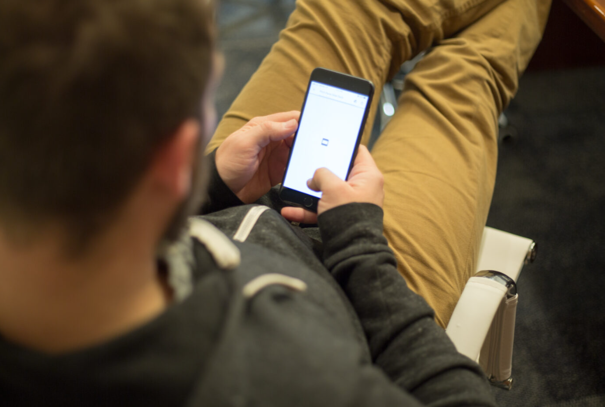 Un jeune homme assis tranquillement consulte son smartphone