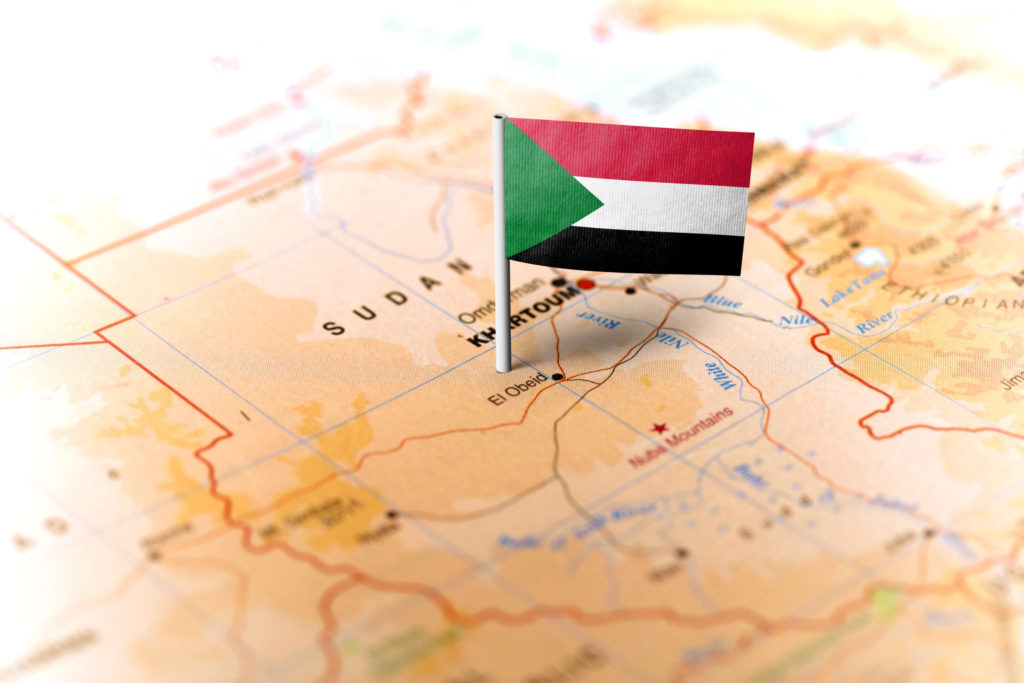 Un petit drapeau du Soudan est planté sur une carte du pays