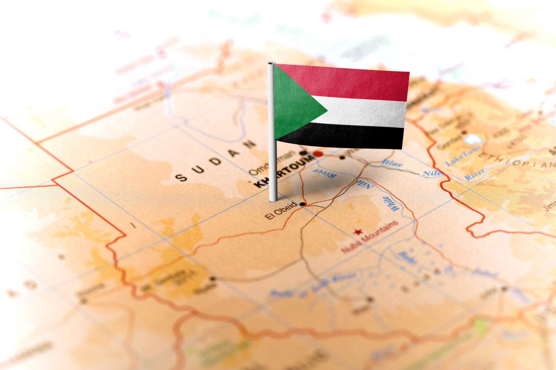 Un petit drapeau du Soudan est planté sur une carte du pays