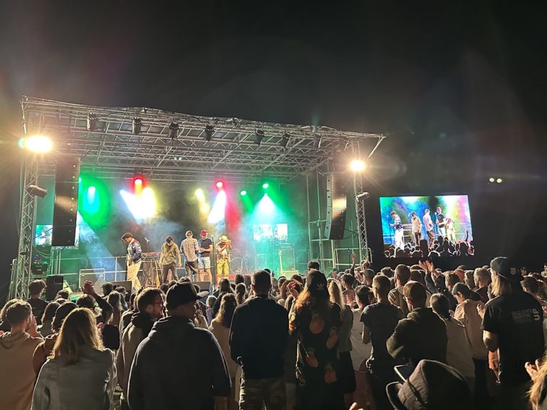 Des festivaliers debout devant la scène du Back'UP, éclairée par des projecteurs