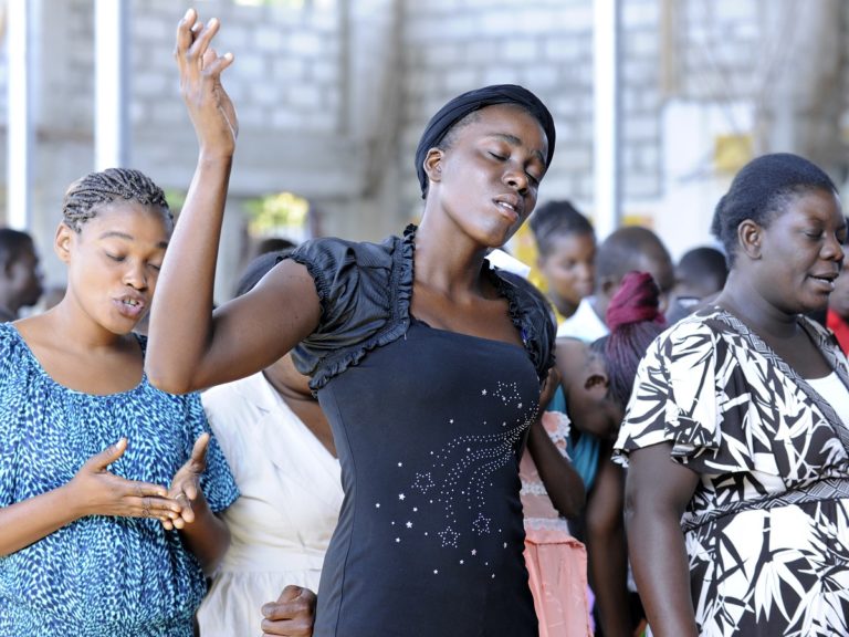Des femmes prient les yeux fermés dans une Eglise en Haïti