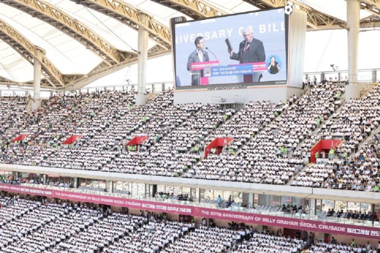 Les tribunes du stade olympique de Séoul remplies avec un écran géant avec Franklin Graham Bible à la main