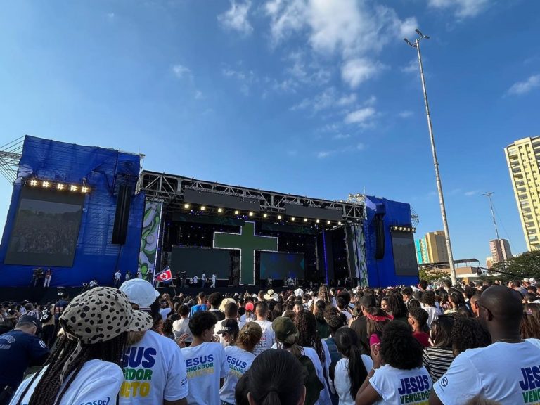 Des chrétiens rassemblés dans les rues de Sao Paulo devant une scène géante avec une croix