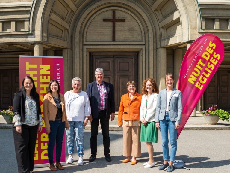 Des bénévoles devant l'Eglise de Fribourg avec des flammes Nuit des Musées