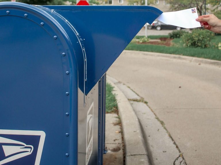 Une personne dépose un courrier dans une boîte aux lettres aux Etats-Unis