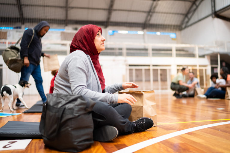 Une dame réfugiée est assise dans un gymnase transformé en lieu d'accueil.