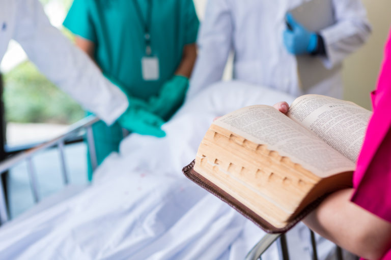 Une personne lit la Bible au chevet d'un patient