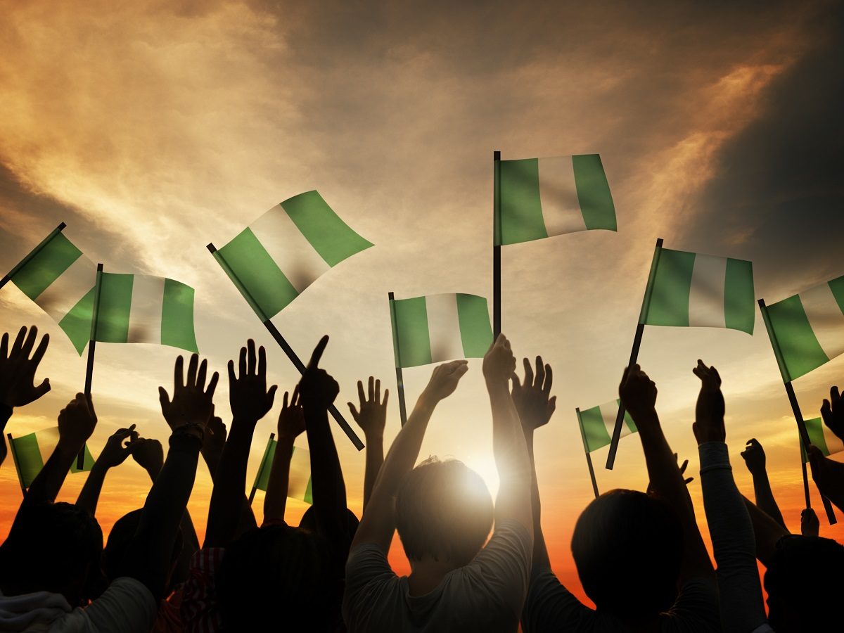 Un groupe de personnes lèvent des drapeaux du Nigéria