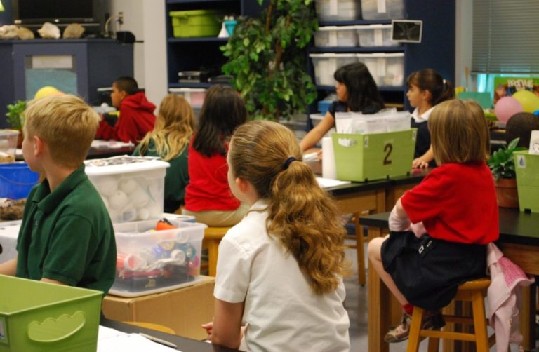 Des enfants assis dans une salle de classe écoutent leur professeur.