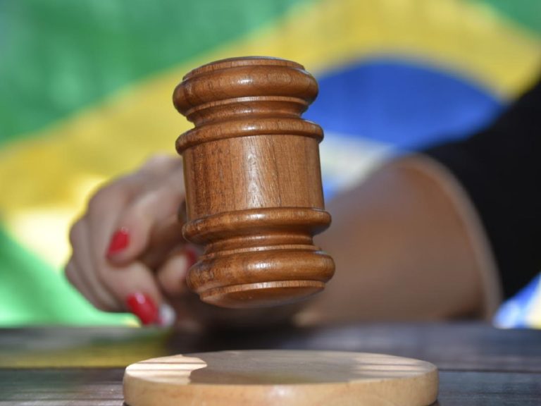 Une femme avec des ongles rouges tient un marteau de justice