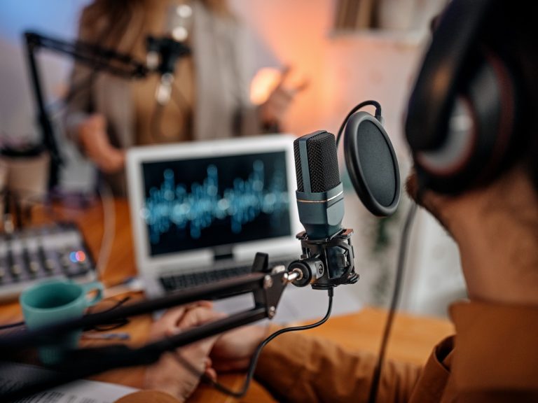 Deux personnes enregistrent un podcast dans un studio de radio avec un micro et un casque sur les oreilles