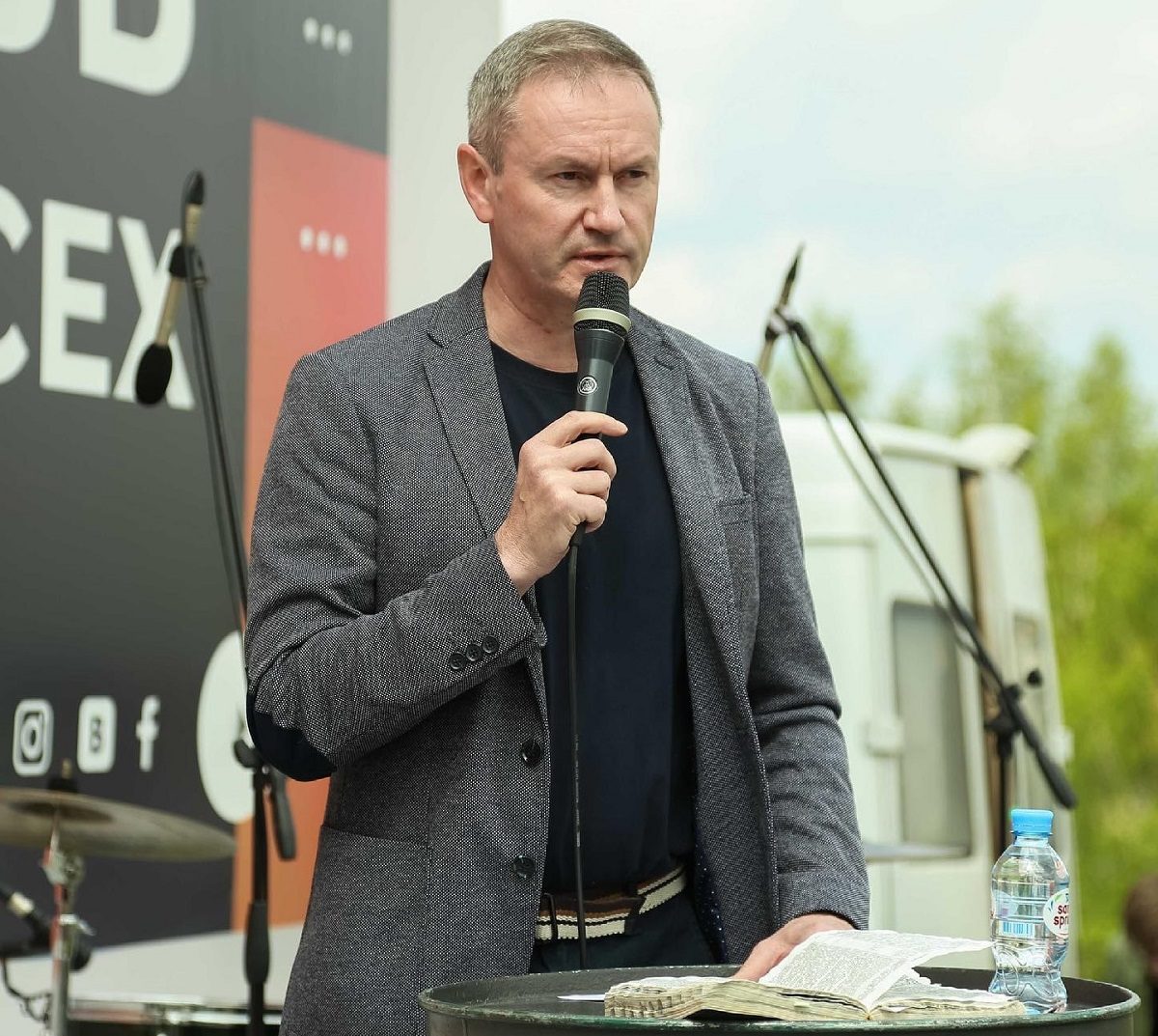 Le pasteur Vyacheslav Goncharenko tient un micro et a une Bible posée sur une table