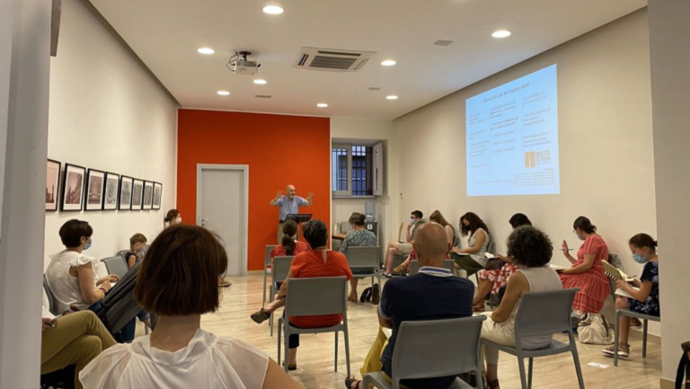 Une quinzaine de personnes assises sur des chaises écoutent le pasteur, dans la petite salle sobre de l'église Facebook / Breccia di Roma