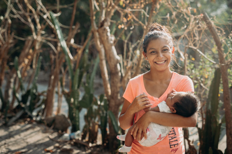 Une maman souriante tient son bébé dans ses bras