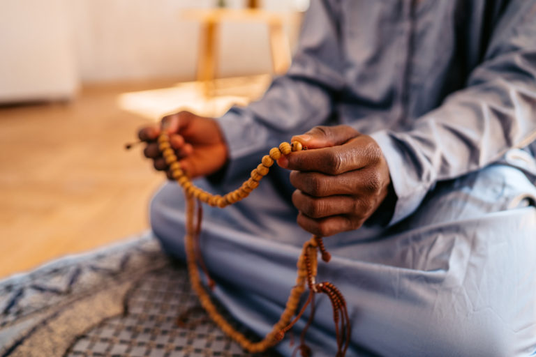 Un musulman assis tient un chapelet de perles de prière