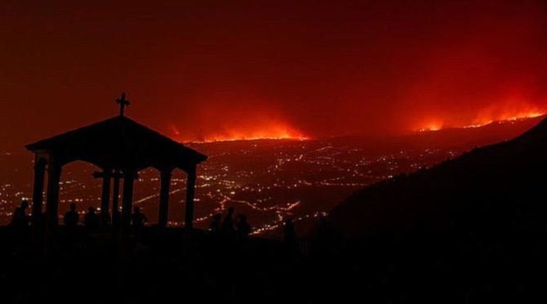 Incendie au loin, près d'une ville éclairée de nuit.