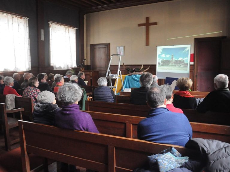 Des croyants assis sur le banc de l'Eglise protestante de Bayeux, une croix en bois est fixée sur le mur