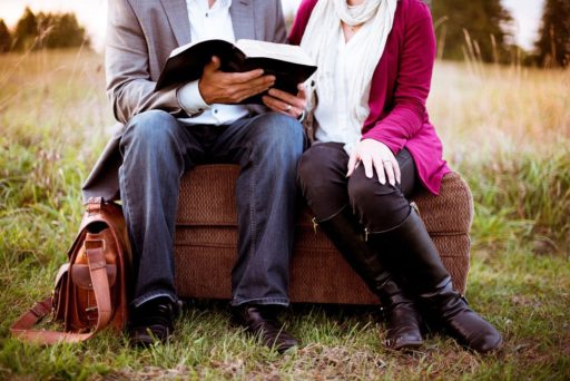 Un homme et une femme assis en extérieur consultent la Bible