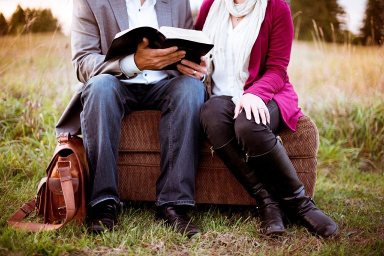 Un homme et une femme assis en extérieur consultent la Bible