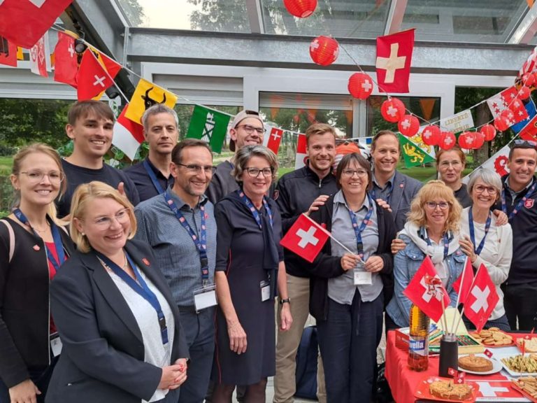 Des bénévoles de l'Armée du Salut Suisse entourés de ballons et drapeaux avec la croix blanche suisse