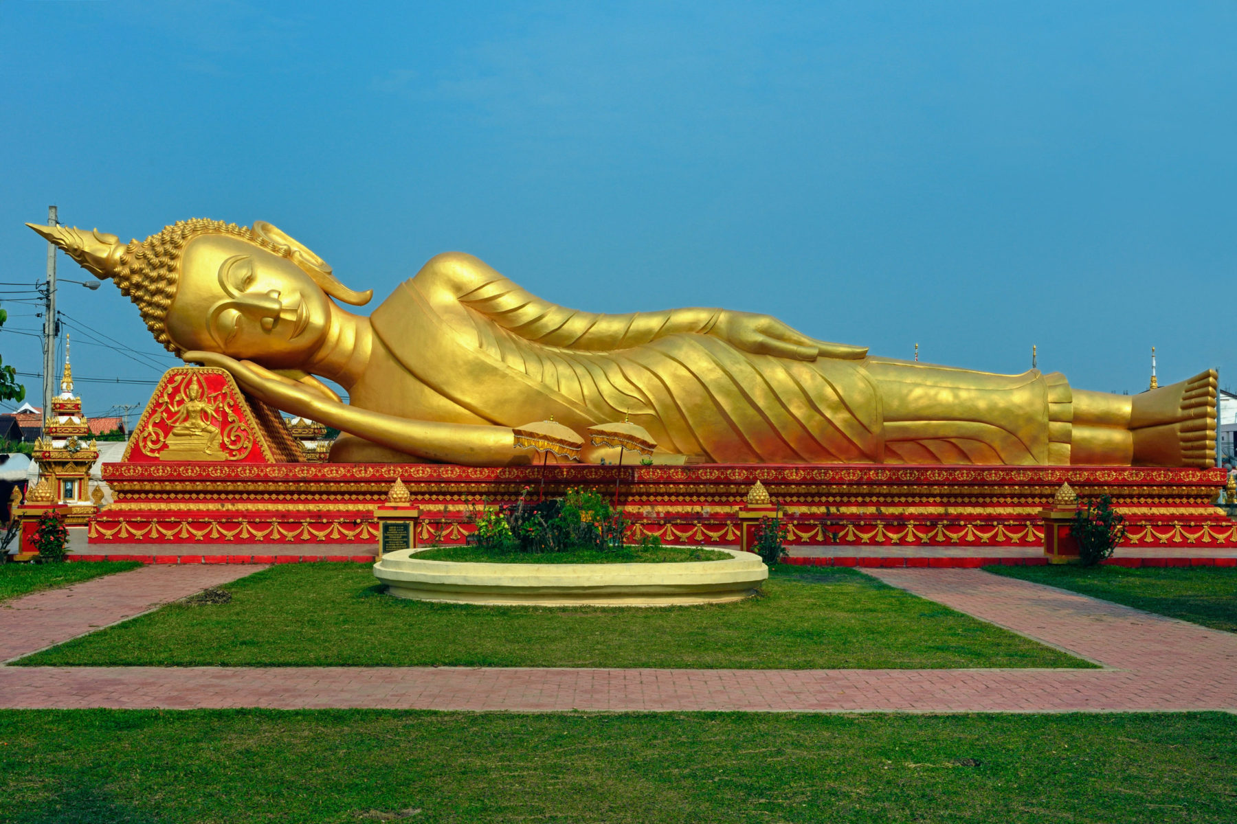 Une statue d'un bouddha couché en longueur et endormi, une main sous le visage, au Laos