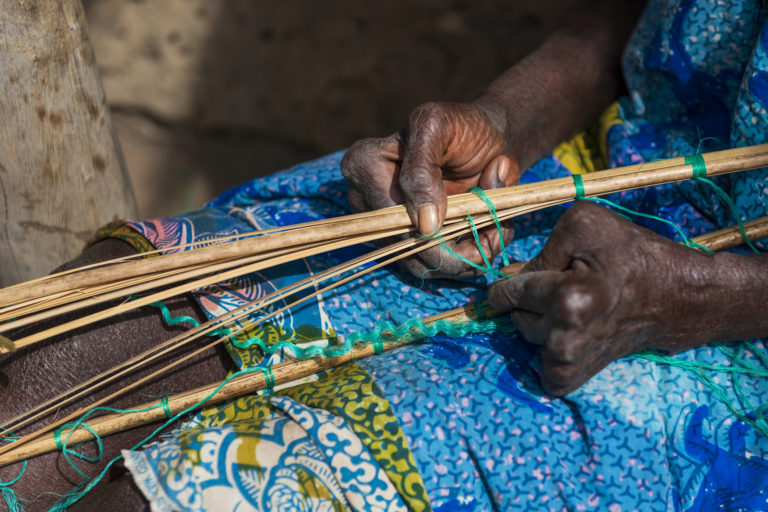 une femme africaine fabrique un objet en roseau