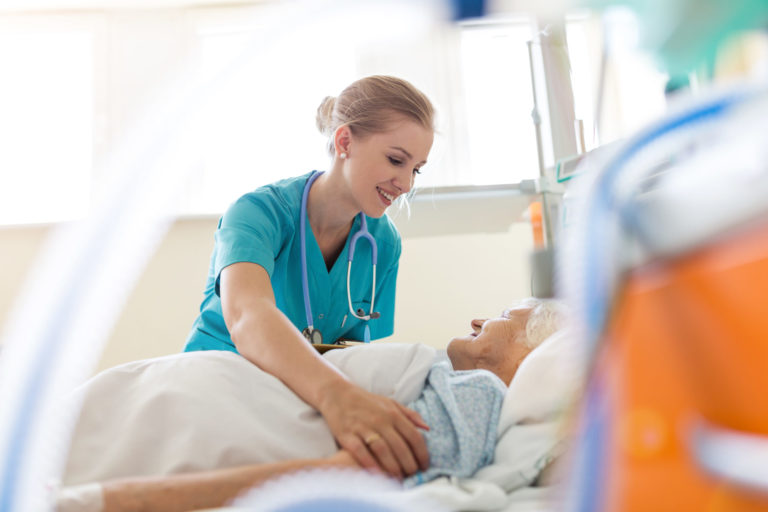 Une jeune infirmière s'occupe d'une personne âgée couchée sur un lit d'hôpital