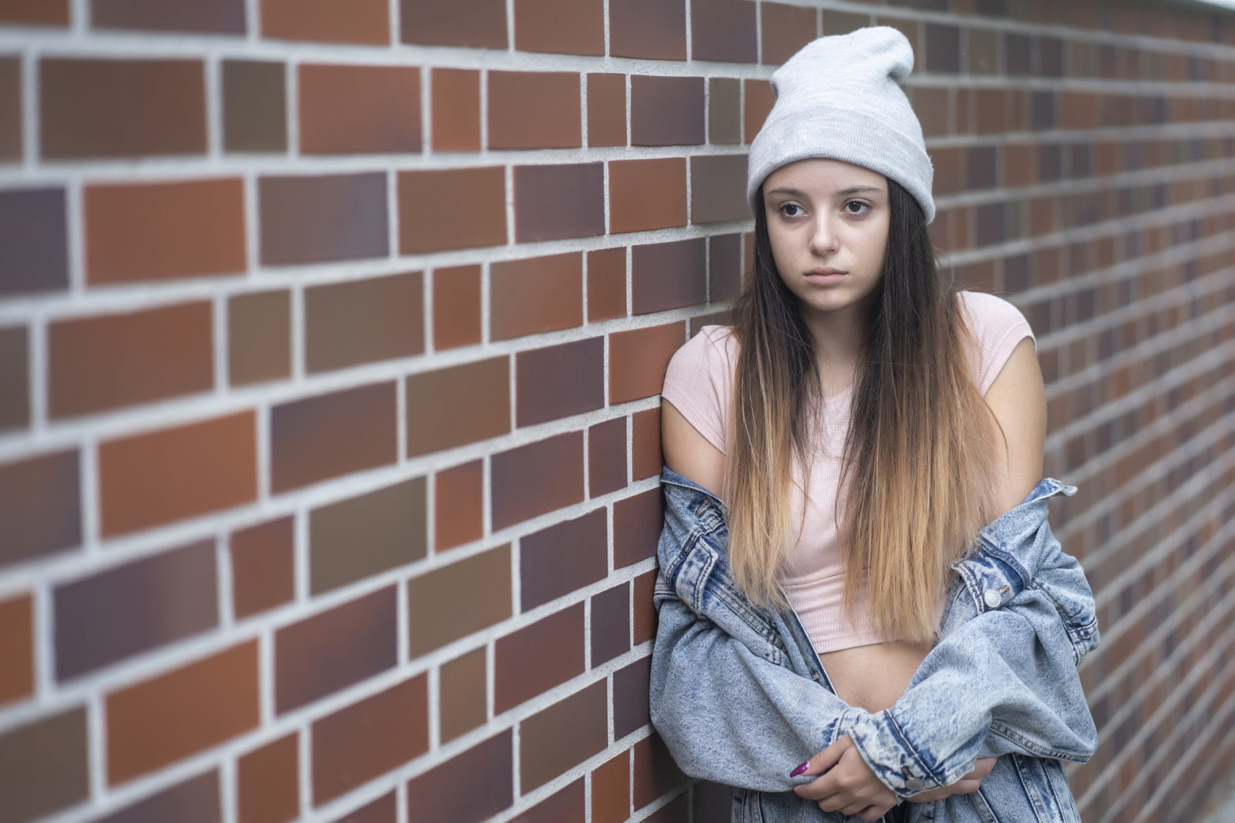 Une adolescente à l'air consterné est appuyée contre un mur.