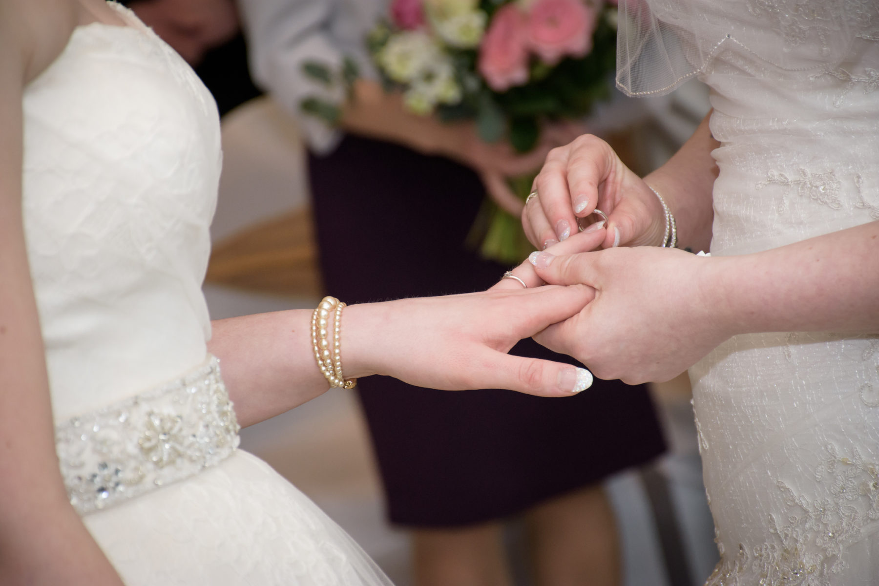 Une femme passe une alliance au doigt de sa conjointe durant leur mariage