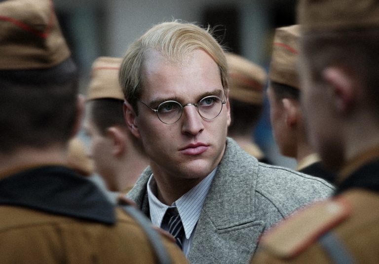 Un homme blond à lunettes fait face à deux militaires SS. Image tirée de l'affiche du film Bonhoeffer