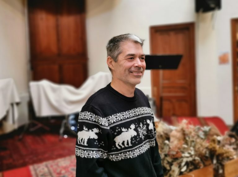 Le pasteur Etienne Linkowski avec un pull de Noël devant l'estrade de l'Eglise évangélique baptiste de Nice