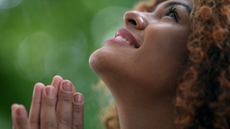 Une femme brésilienne souriante prie en regardant vers le ciel