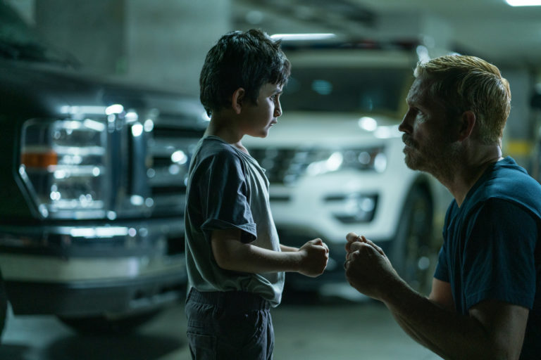 L'acteur Jim Caviezel fait un "check" avec ses poings à un enfant dans un parking souterrain. Image tirée du film Sound of Freedom