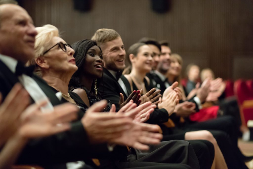 le premier rang d'une foule, assis, applaudit lors d'un événement