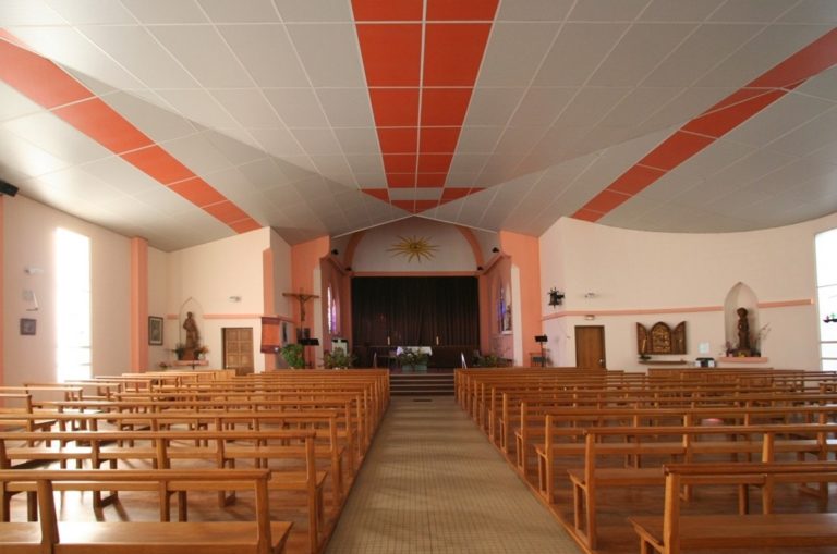Vue de l'intérieur d'une église catholique avec des bancs et un autel au fond