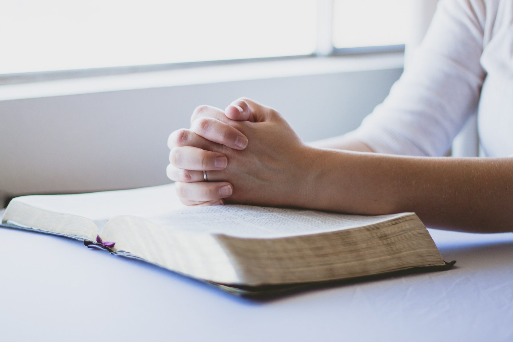 Les mains d'un homme posées sur la Bible, en train de prier