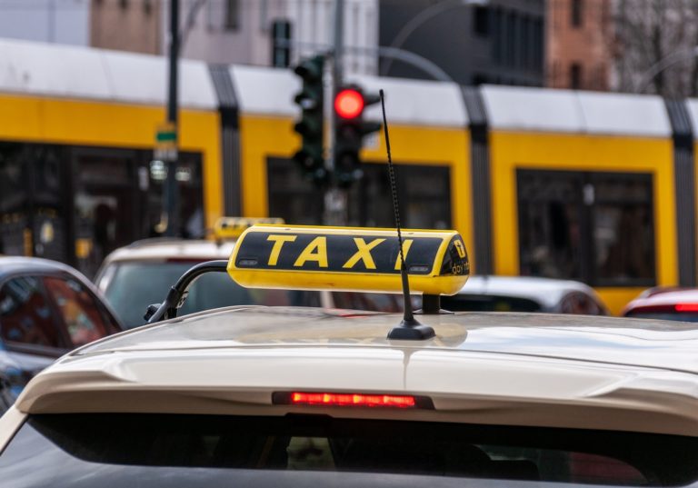 Le toit d'une voiture avec l'inscription taxi, un feu de circulation et un tramway