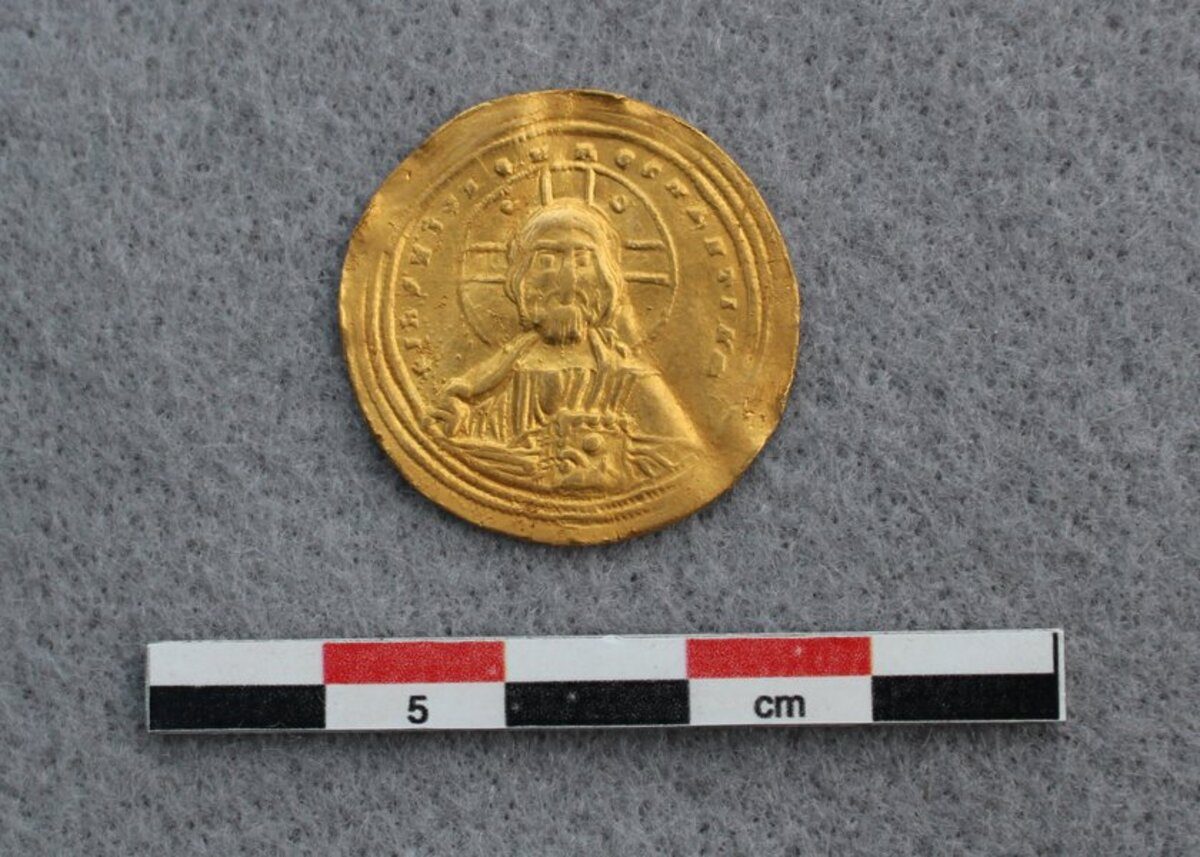 La pièce en or représentant Jésus tenant une Bible. Elle mesure environ 5 cm.