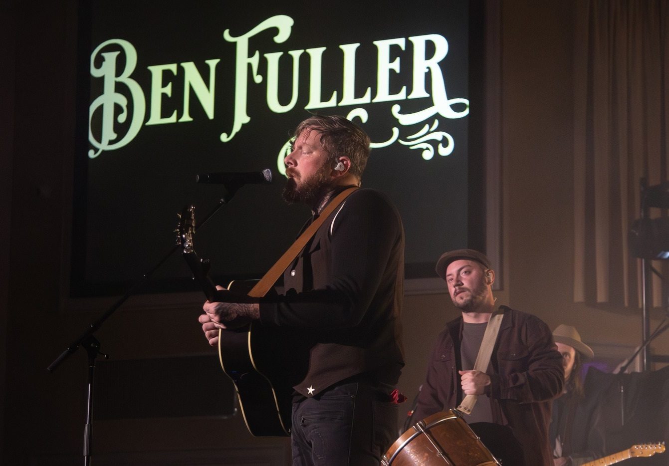 Ben Fuller joue de la guitare et chante, un percussionniste l'accompagne au second plan