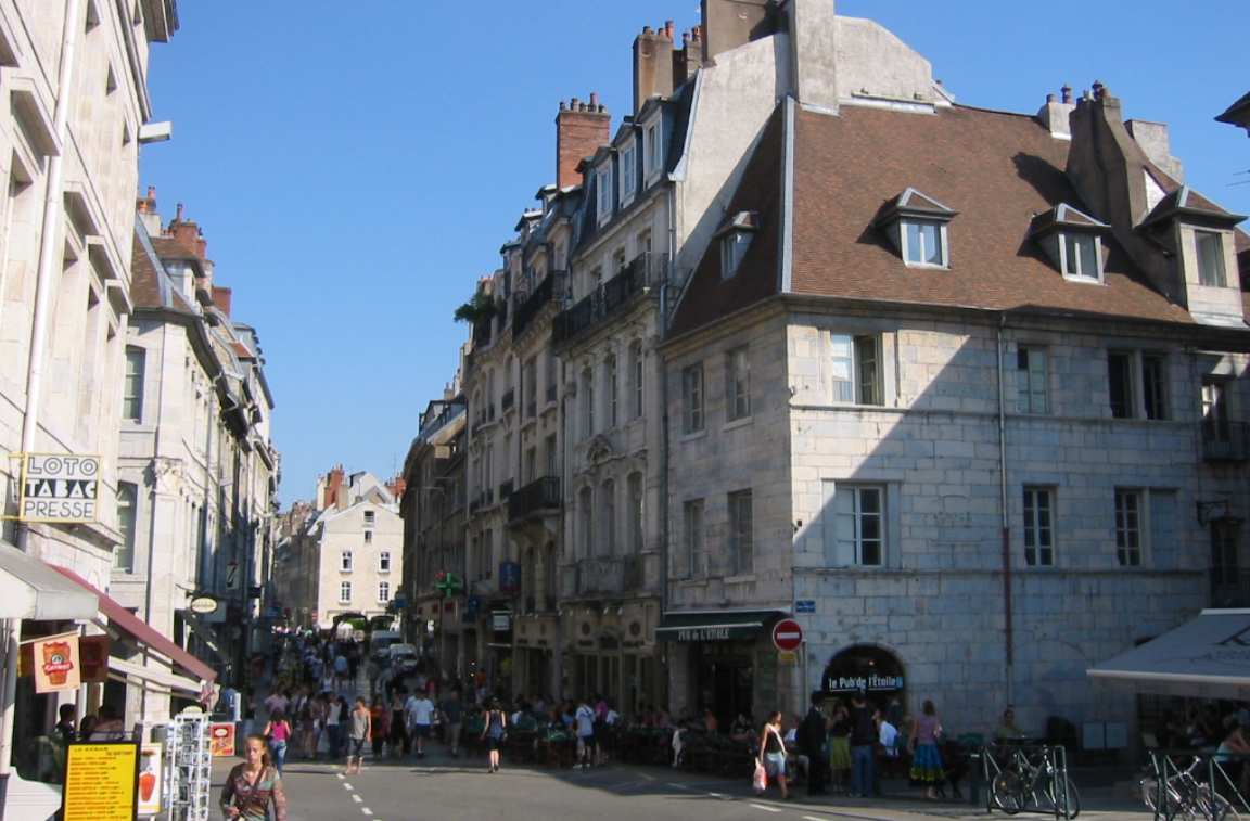 Une longue rue piétonne à Besançon. Il fait beau et il y a beaucoup de monde.