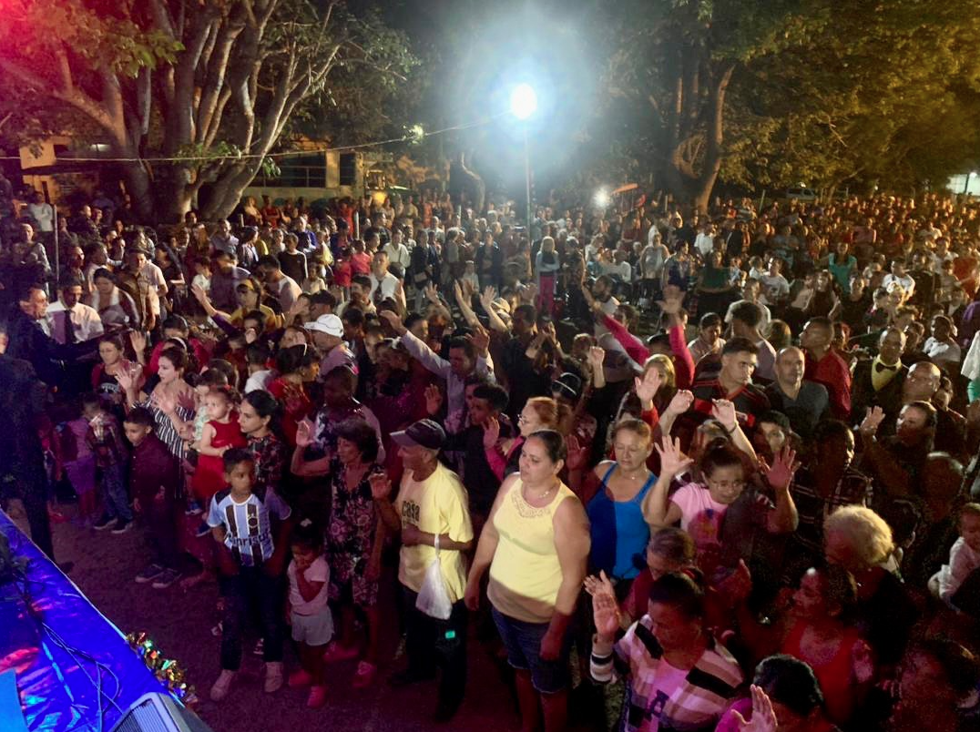Une foule rassemblée dans la rue de la ville Báguanos située à l’Est de Cuba. Les personnes lèvent les mains et ferment les yeux.