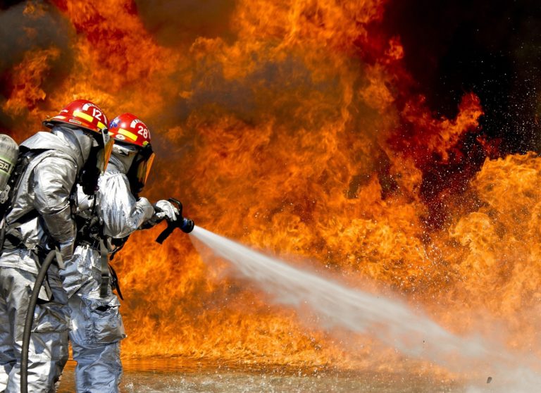 Deux pompiers face aux flammes avec une lance d'eau