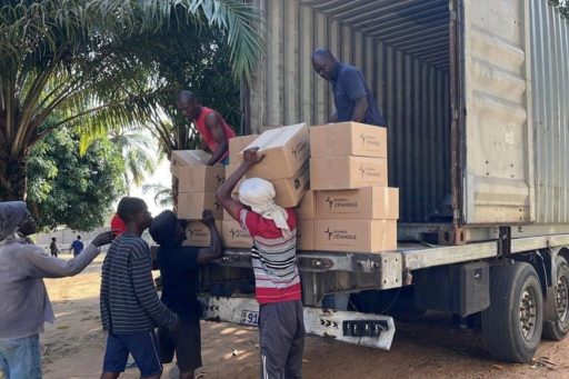 Des hommes déchargent des cartons d'un camion remplis de livres chrétiens au Togo